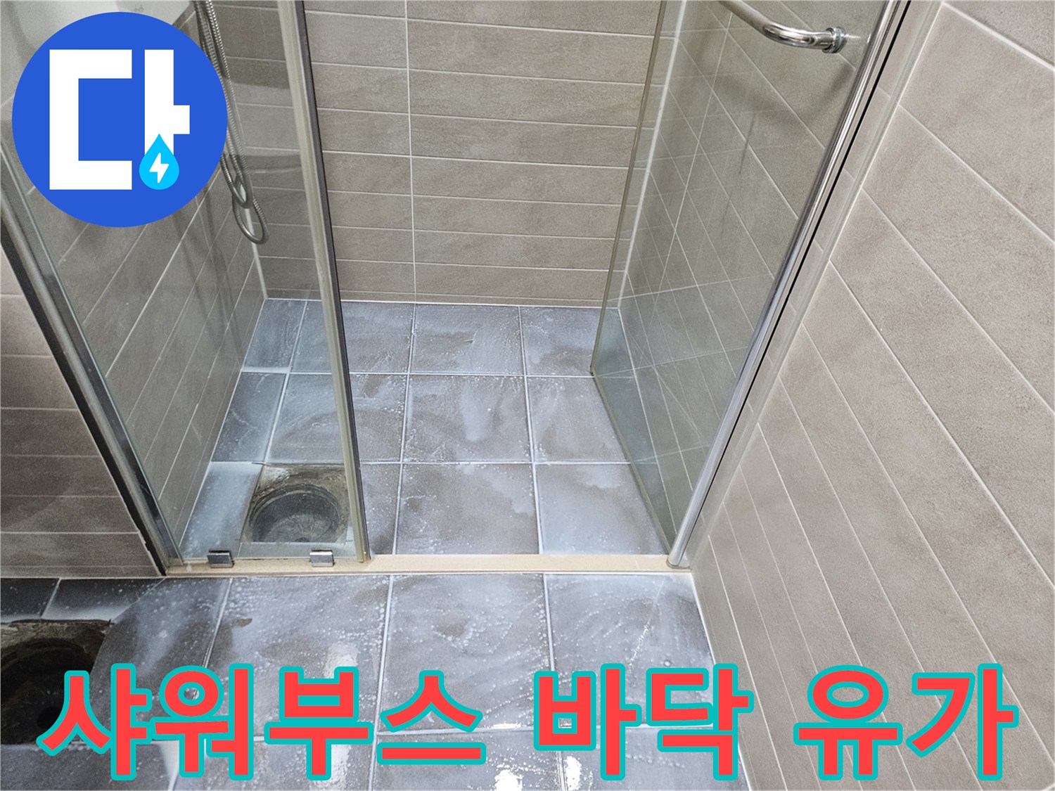 샤워 부스 내 배수구와 주변 타일의 모습입니다.