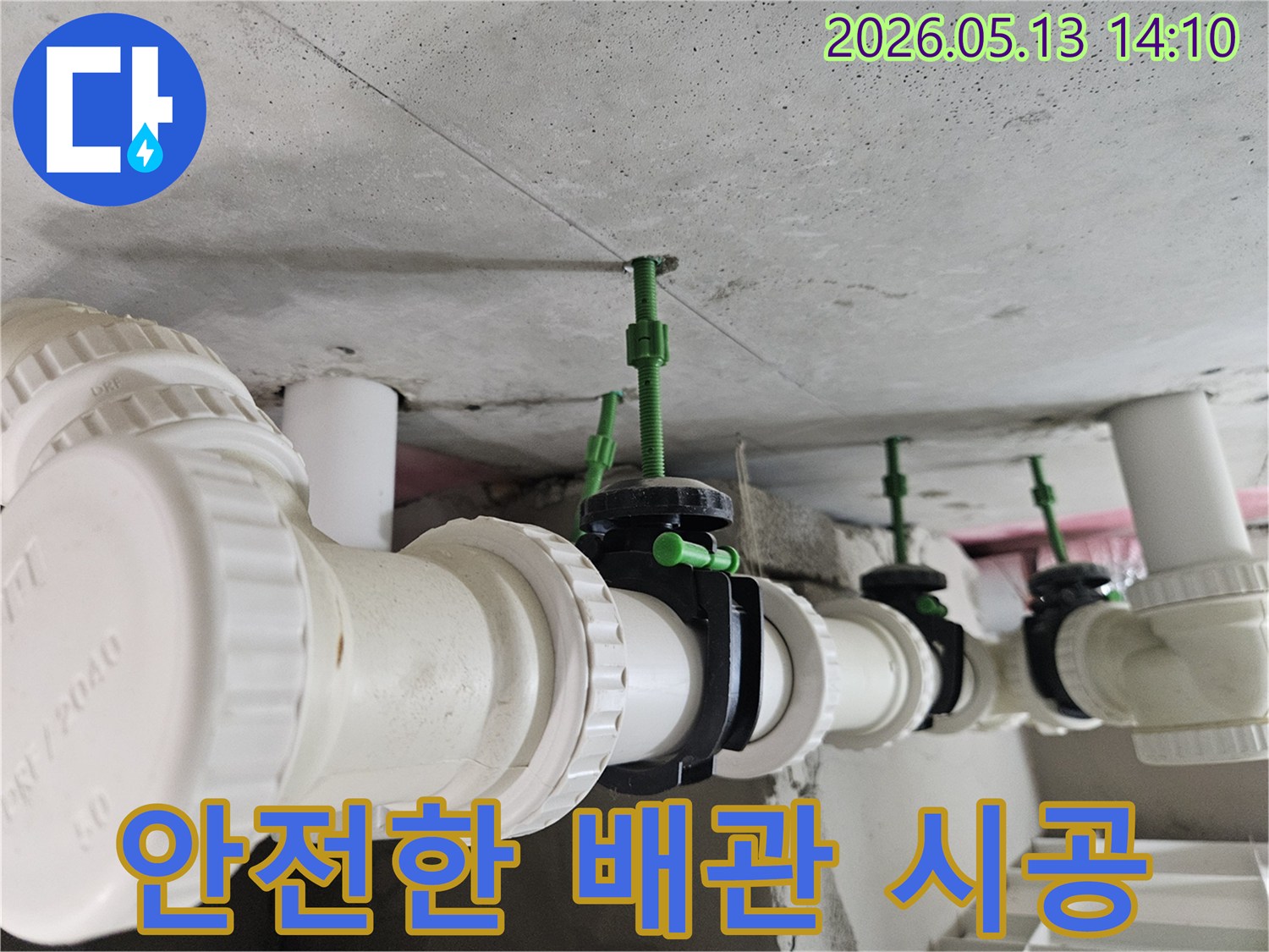 콘크리트 천장에 안전하게 설치된 흰색 배관과-검은색 밸브들이 누수 위험 없이 견고하게 연결된 모습