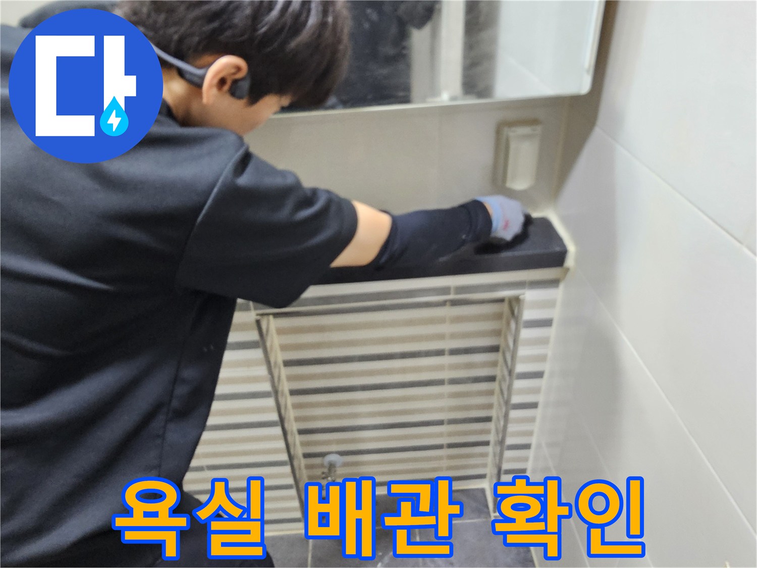 세면대 아래쪽 배관 연결 부위의 물샘 흔적을 찾는 작업자