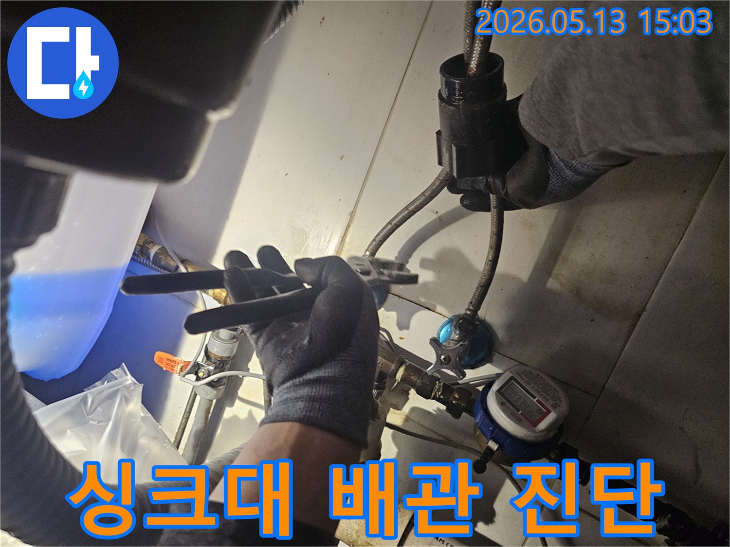장갑 낀 손이-수도 계량기 근처의-배관 연결부를-점검하는 모습