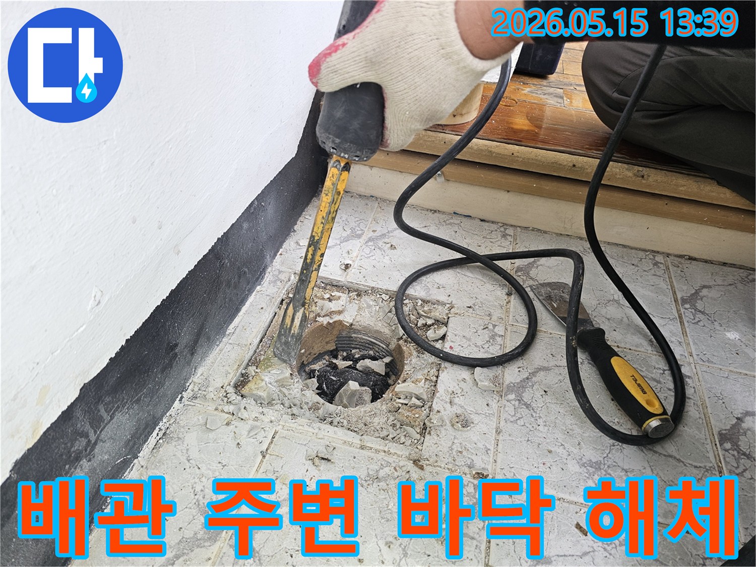 누수 공사를 위해 배관 주변의 바닥 타일을 해체하는 작업자의 모습