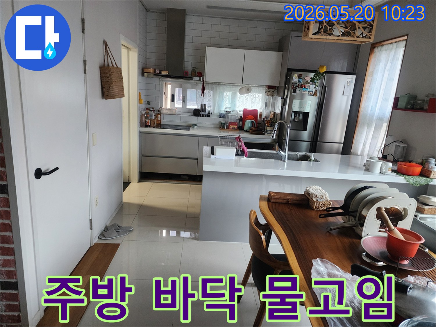 현대적인 주방의 흰색 타일 바닥에 물이 고여-누수 현장을 보여주는 이미지