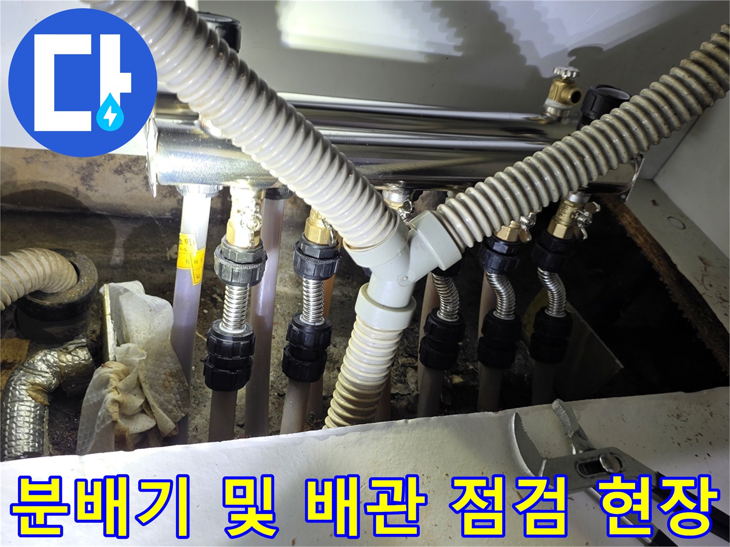 싱크대 하단 분배기에 연결된 여러 개의 호스와 금속 부속들