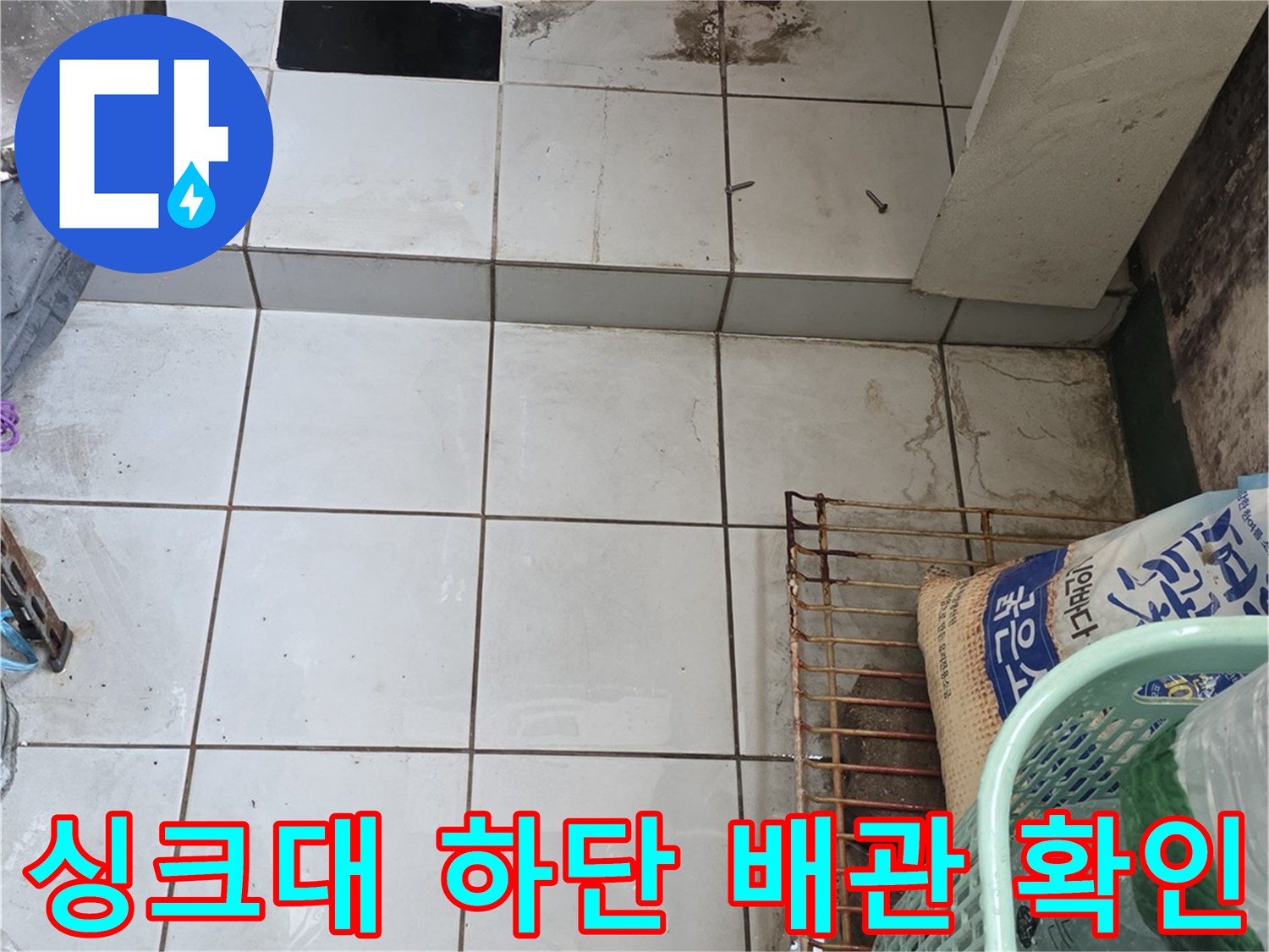 주방 싱크대 밑 파란색 배관과 타일 벽면의 근접 사진