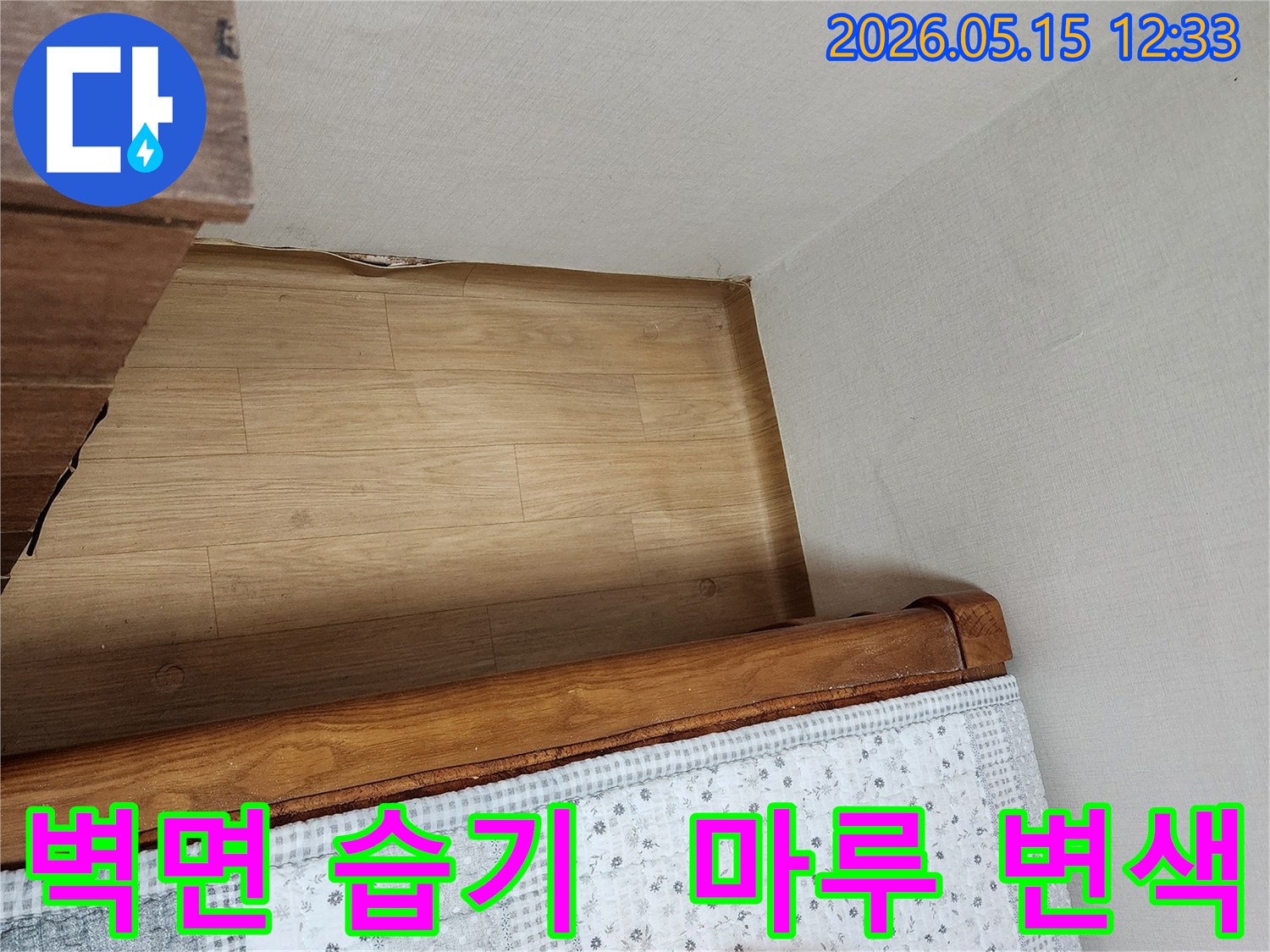 침대-옆-벽면의-습기-자국과-바닥-마루의-변색-정도를-보여주는-현장-사진입니다