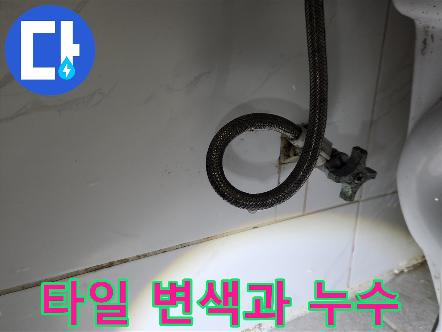 수도-앵글밸브-아래-누수로-인해-타일-줄눈이-검게-변색된-현장을-손전등으로-비춰-보여주는-사진