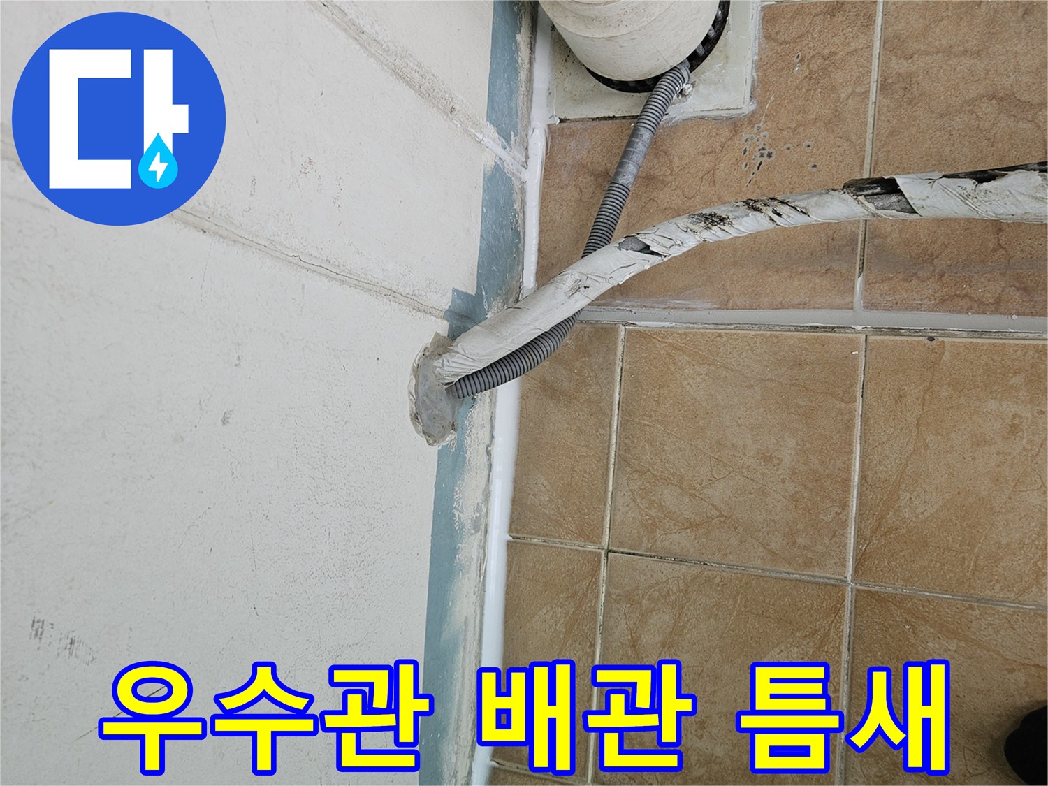 아파트 베란다 우수관과 벽면 타일 사이의 벌어진 틈을 보여주는 사진입니다.