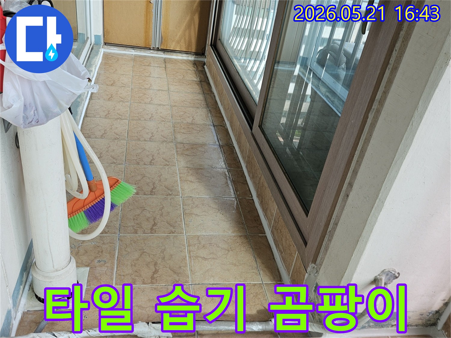 아파트 베란다 타일 벽면의 습기 흔적과-배관 주변의 상태를 보여주며-누수로 인한 곰팡이 발생 여부를 점검하는 현장입니다.