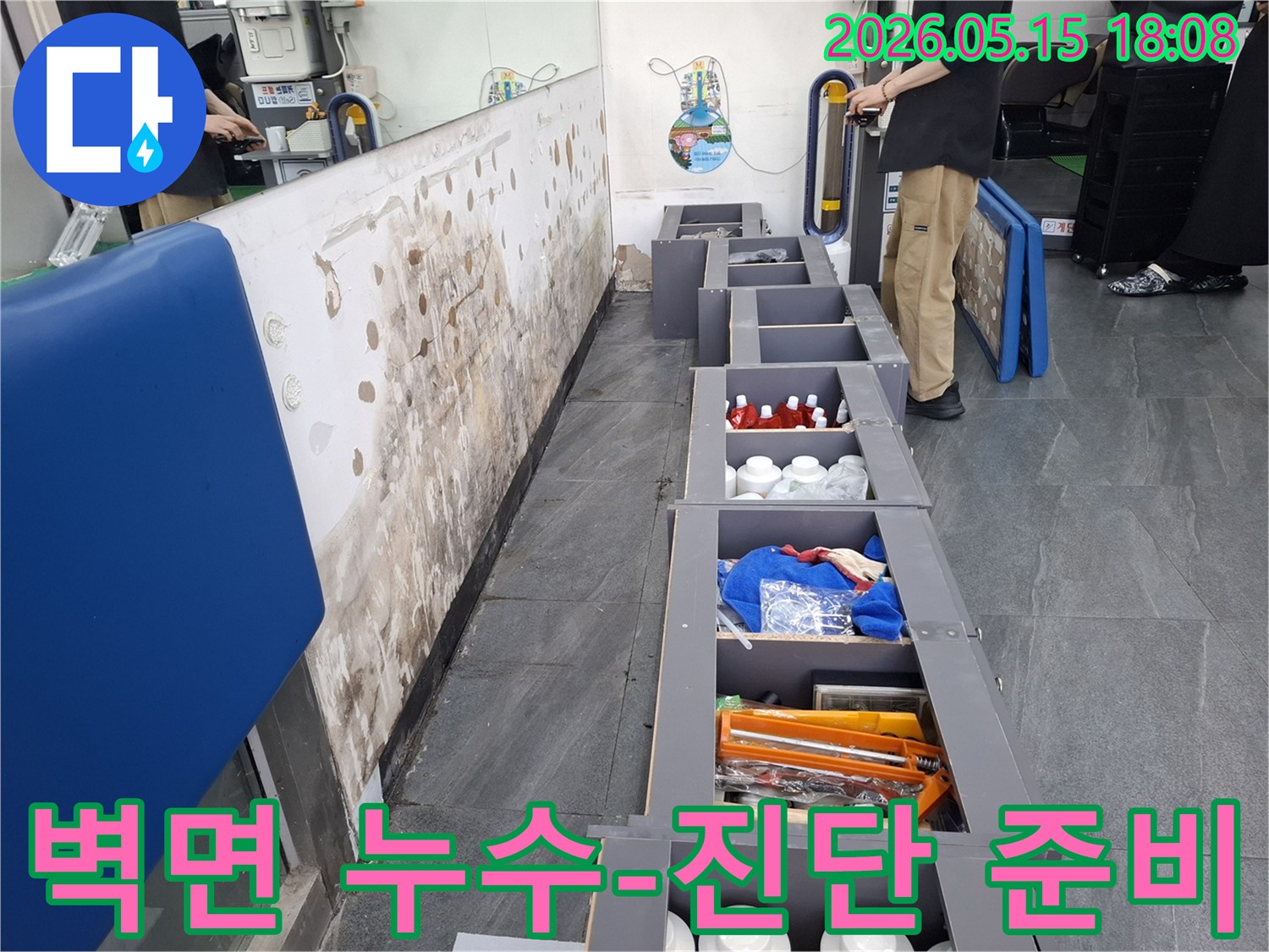 누수로 인해 손상된 벽면과-탐지 작업을 위해-정리된 주변 공간을-보여주는 현장 사진입니다