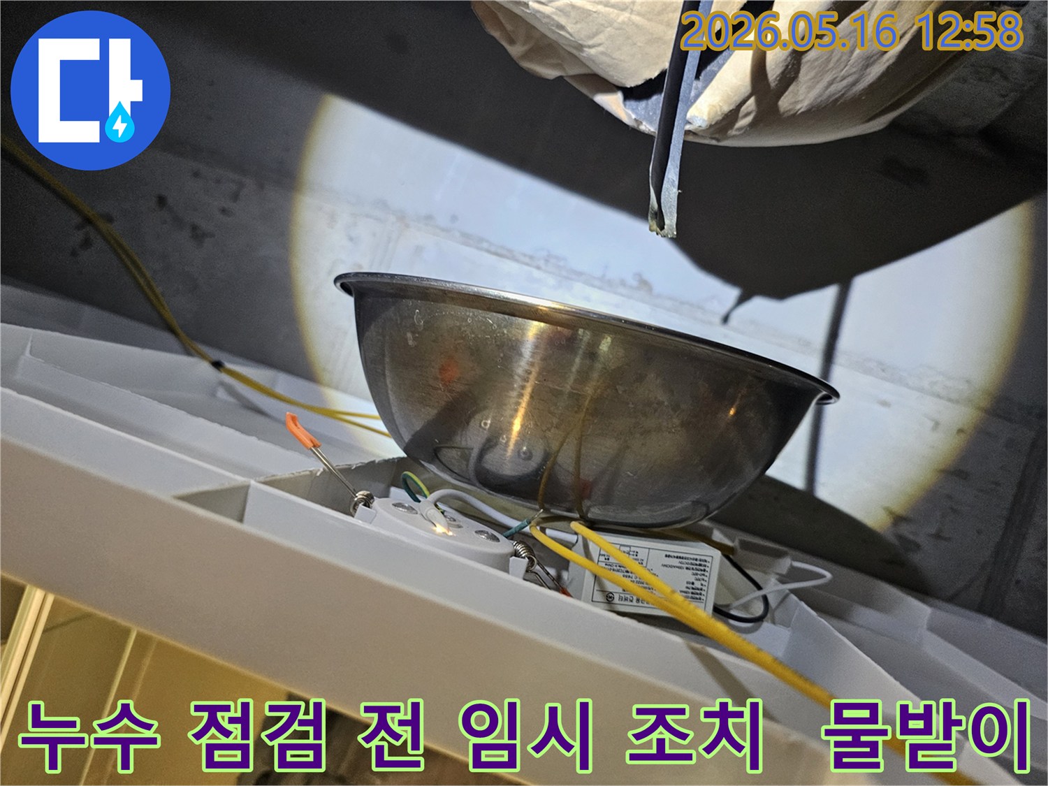 누수 점검 작업을 시작하기 전-천장에서 물이 떨어지는 것을-스테인리스 볼로-받아내며-주변의 전기 배선과-조명 장치를-보호하는 모습