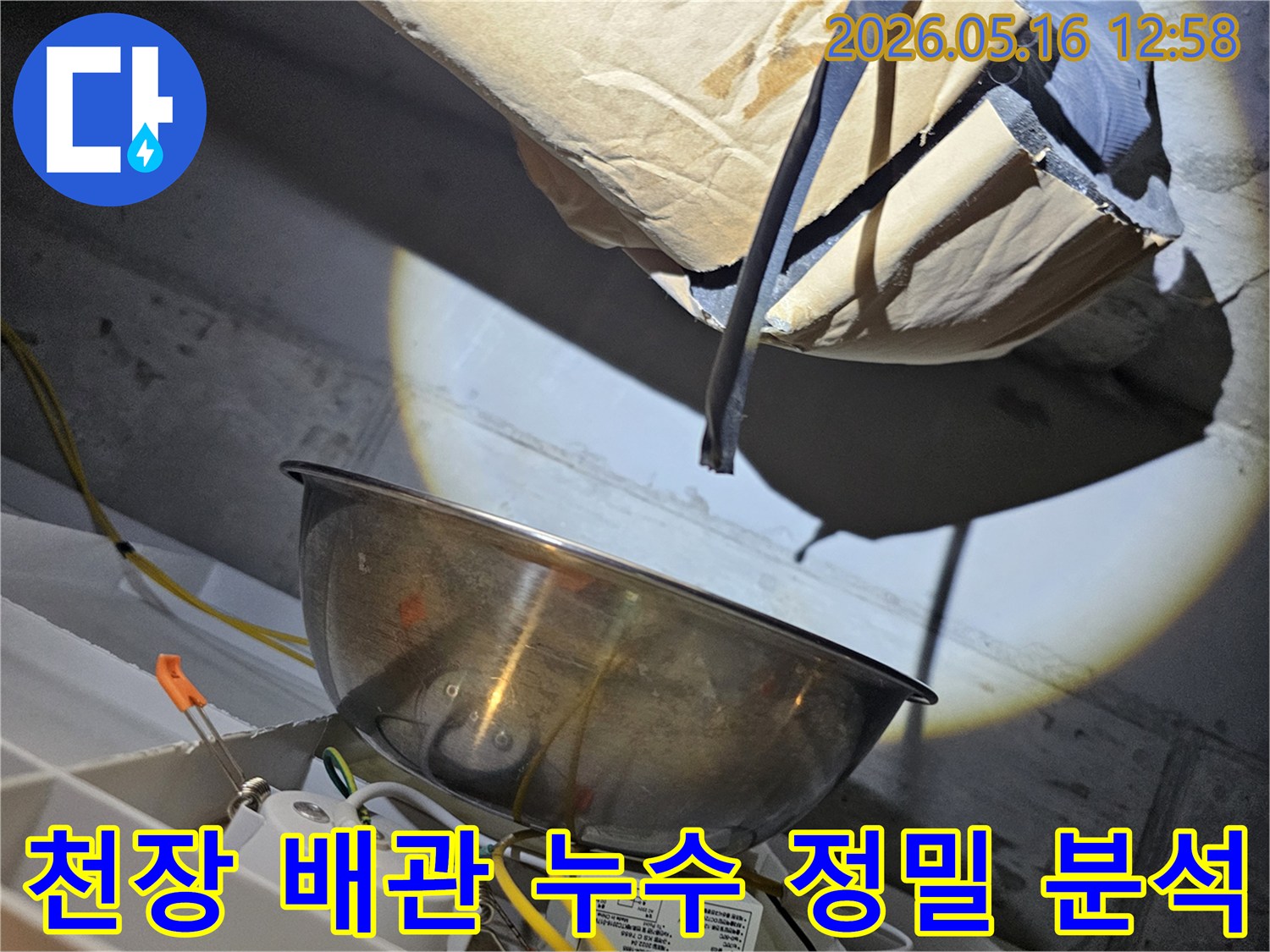 어두운 천장 속에서-강력한 조명으로-배관의 미세한 누수 지점을-정밀하게 분석하는-전문가의 모습입니다