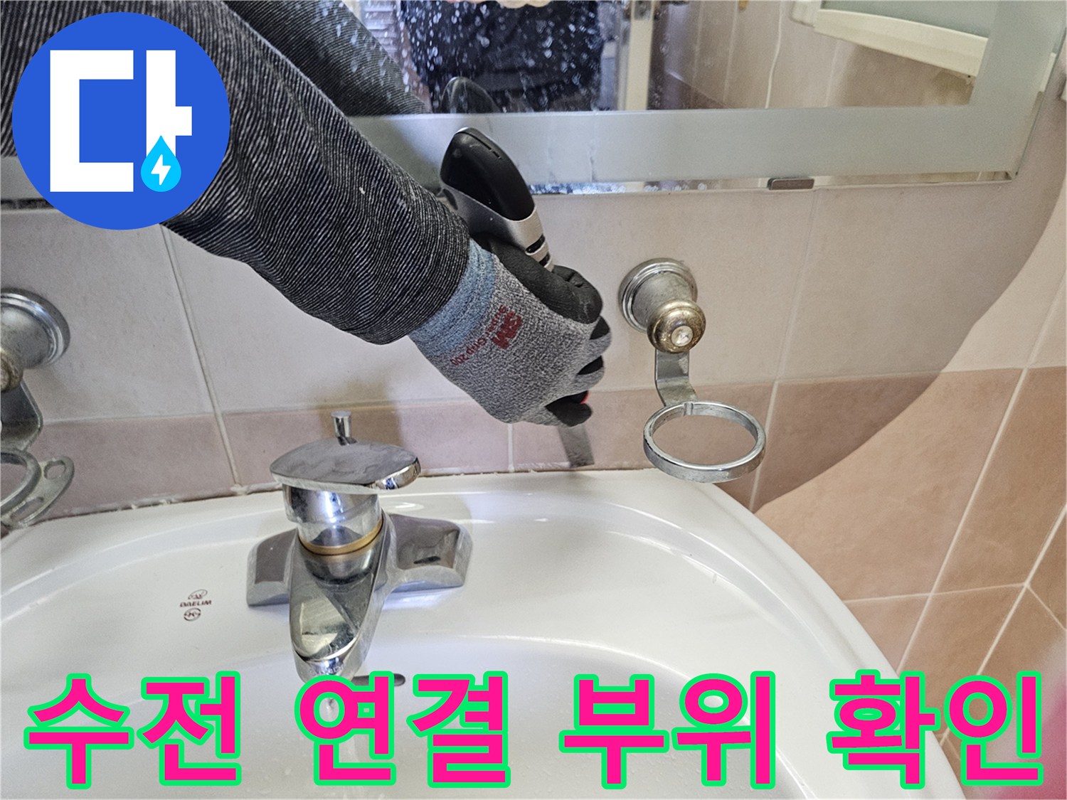 작업자가 장갑을 착용한 채로 세면대 수전 뒤쪽의 배관 고정 상태를 점검하고 있습니다.