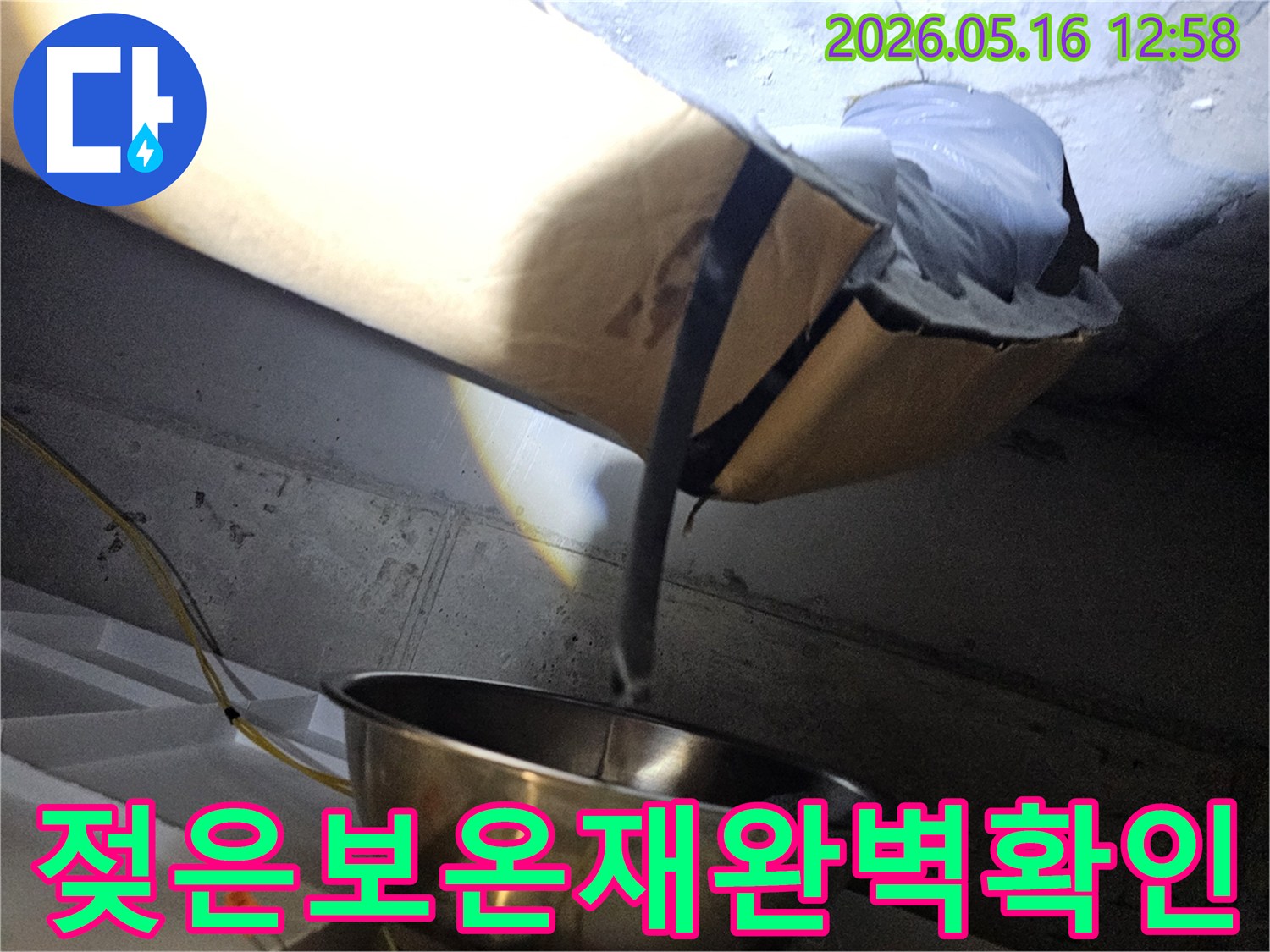 천장 내부의-어두운 공간에서-누수로 인해 젖은-보온재를 조명으로 비춰-확인하는 현장 모습입니다.