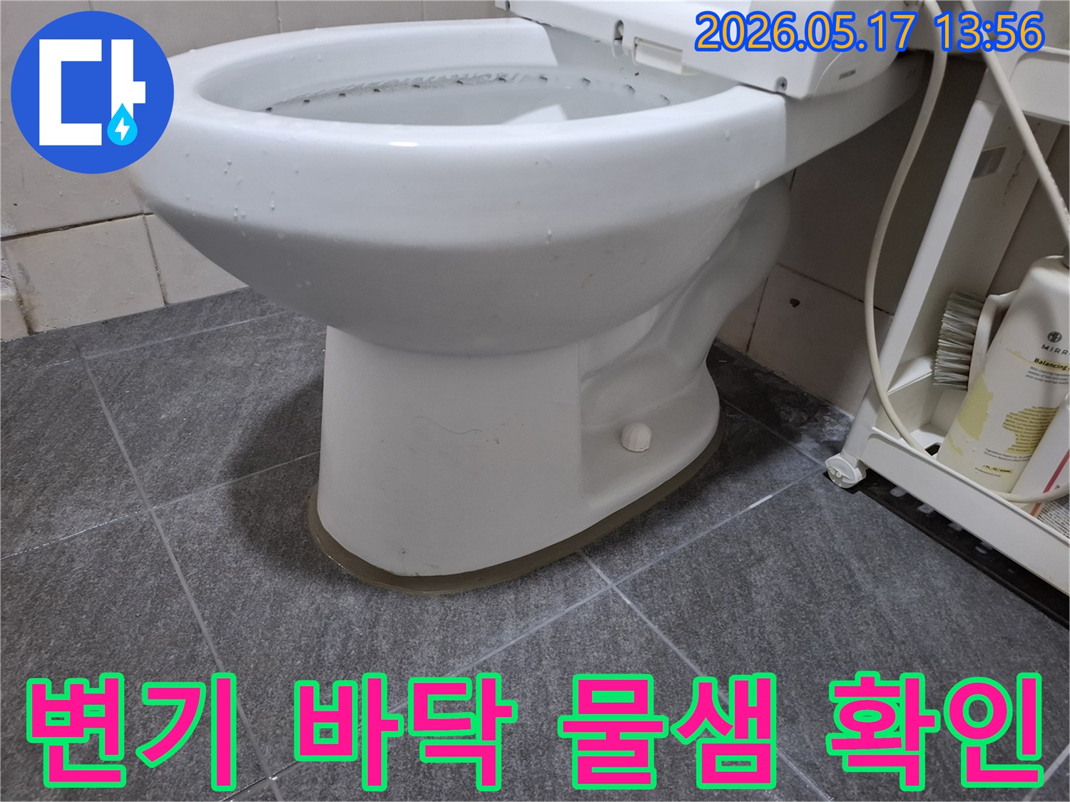 변기 하단과 바닥 타일 사이로-물이 새어 나와 고여있는-누수 흔적을 보여주는 클로즈업 사진