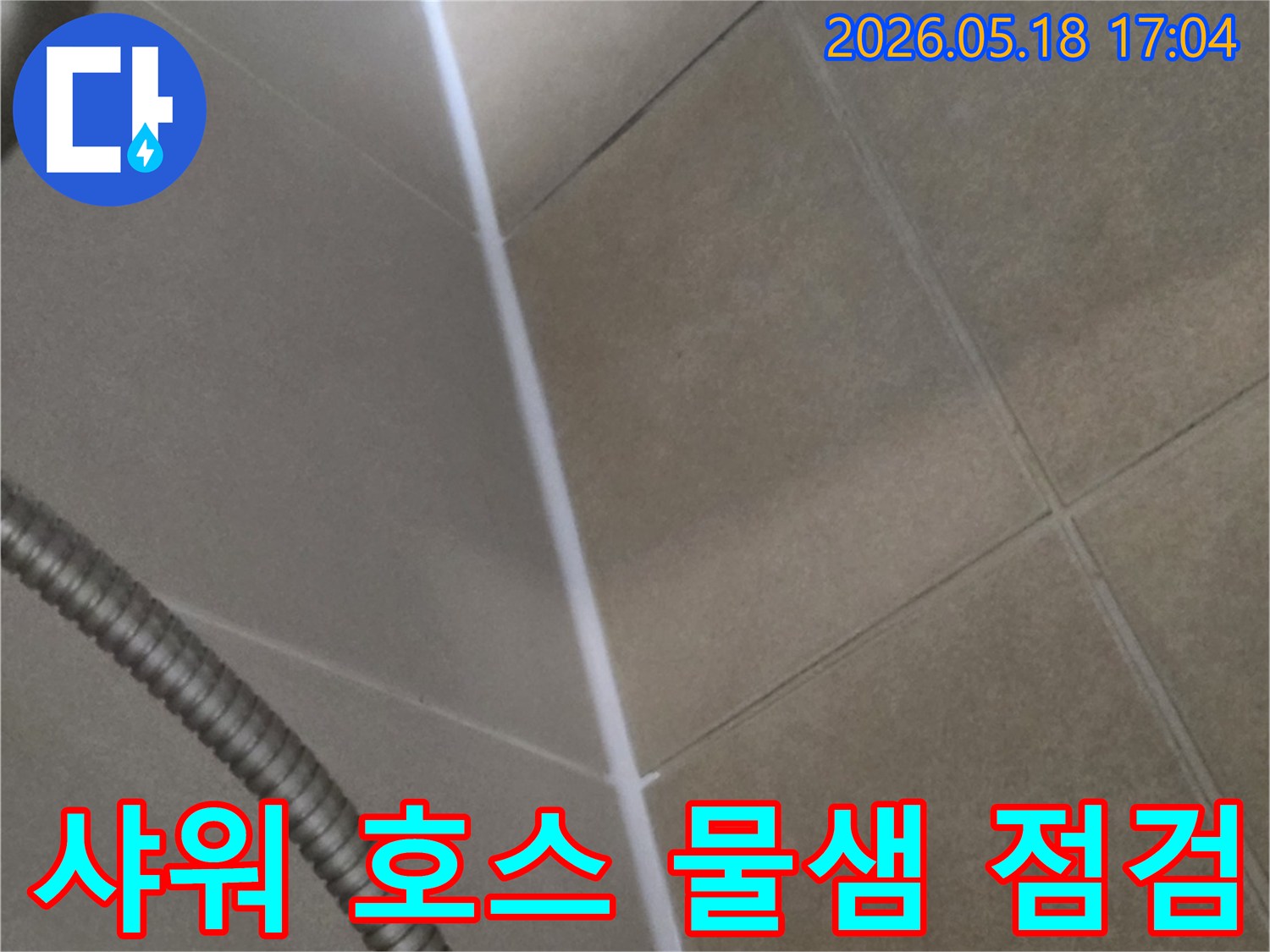 욕실 샤워 호스 주변의 바닥 타일과 벽면-물샘 가능성을 점검하기 위해-타일과 줄눈 상태를 면밀히 관찰하는 모습입니다