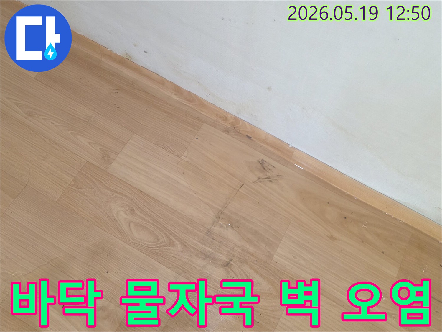 바닥 마루와 벽면 하단에 누수로 인한 물자국과 오염이 명확한 현장 사진입니다