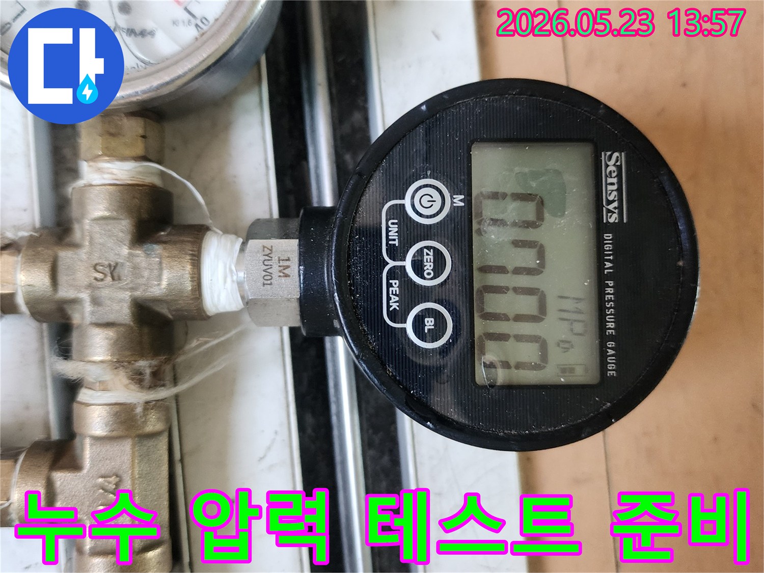 누수 탐지 과정에서 배관의 압력 변화를 측정하기 위해 디지털 압력계를 연결하고 있는 장면입니다.