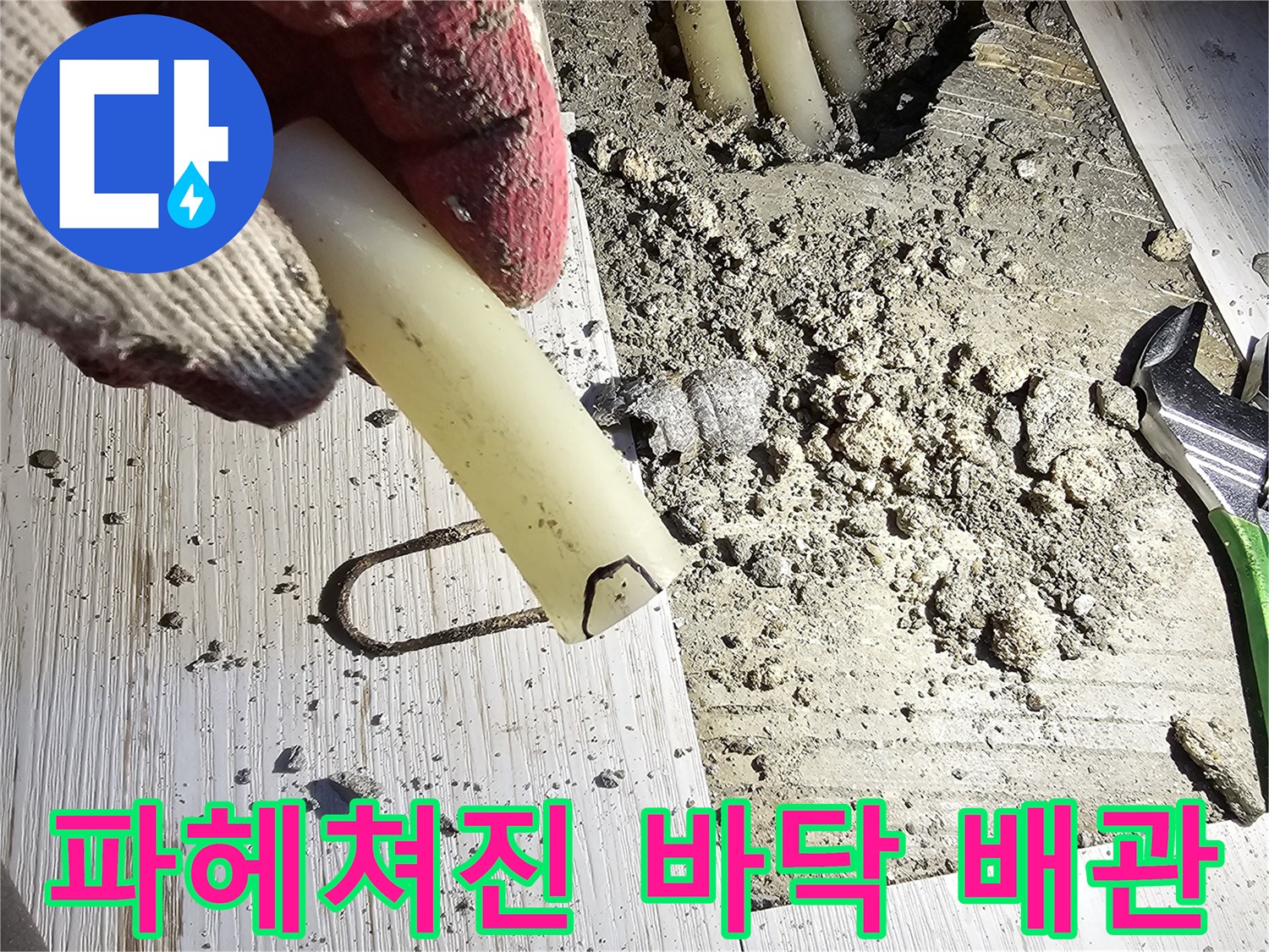 굴착된 콘크리트 바닥 사이로 노출된 흰색 배관 부속