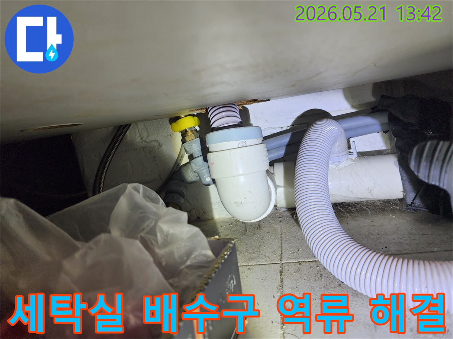 세탁실 바닥 배수구에서 발생하는 역류 현상을 해결하기 위해-배수관 내부를 점검하고 이물질을 제거하는 작업 현장입니다.
