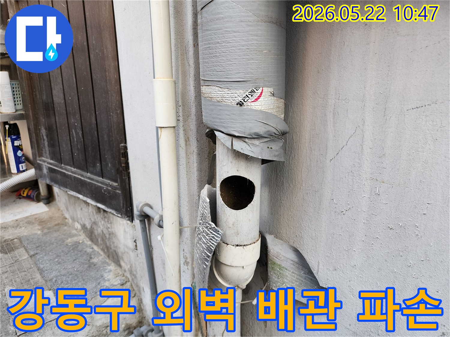 오래된 주택의 외벽에 설치된-파손된 배수관을 보여주는 이미지입니다