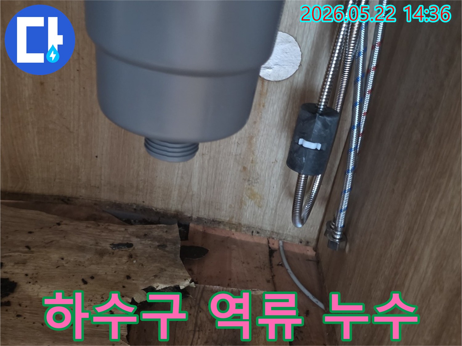 싱크대 하부장 내부의 하수구 배관 주변에서 발생한-역류로 인한 물샘 흔적과-손상된 목재를 보여주는 현장 사진