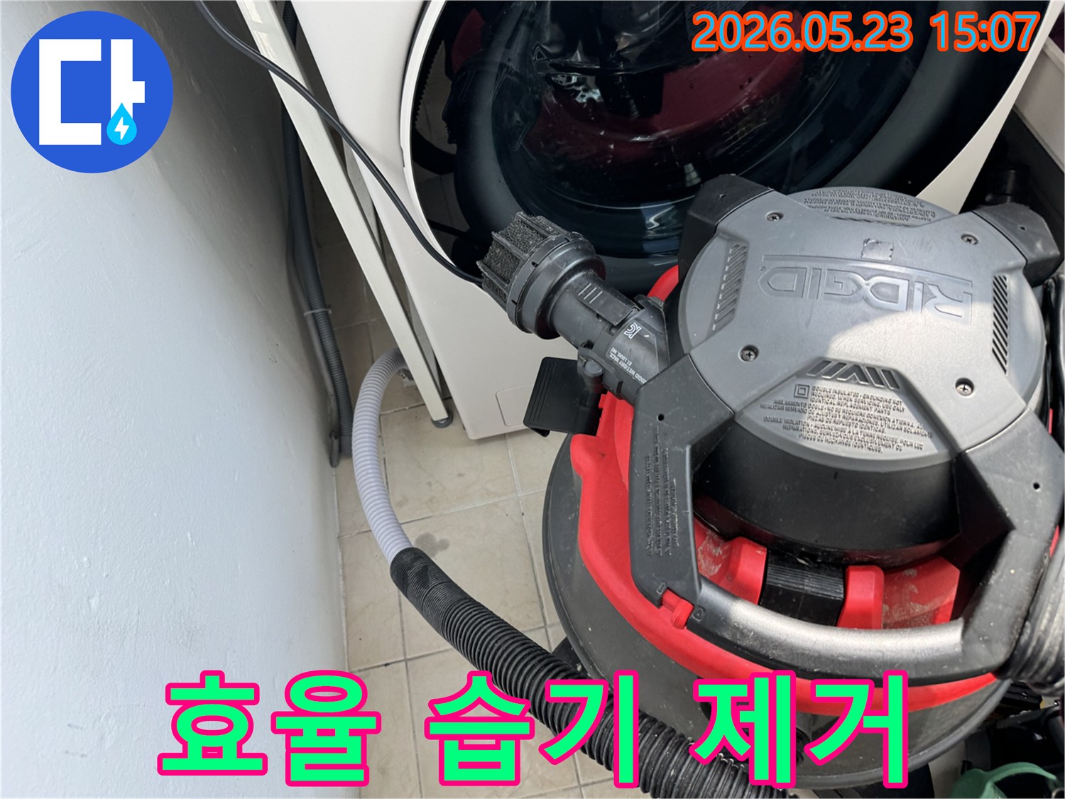 세탁기 옆-바닥에 고인 물을-전문 흡입기로 제거하는-누수 현장 복구 작업 사진입니다