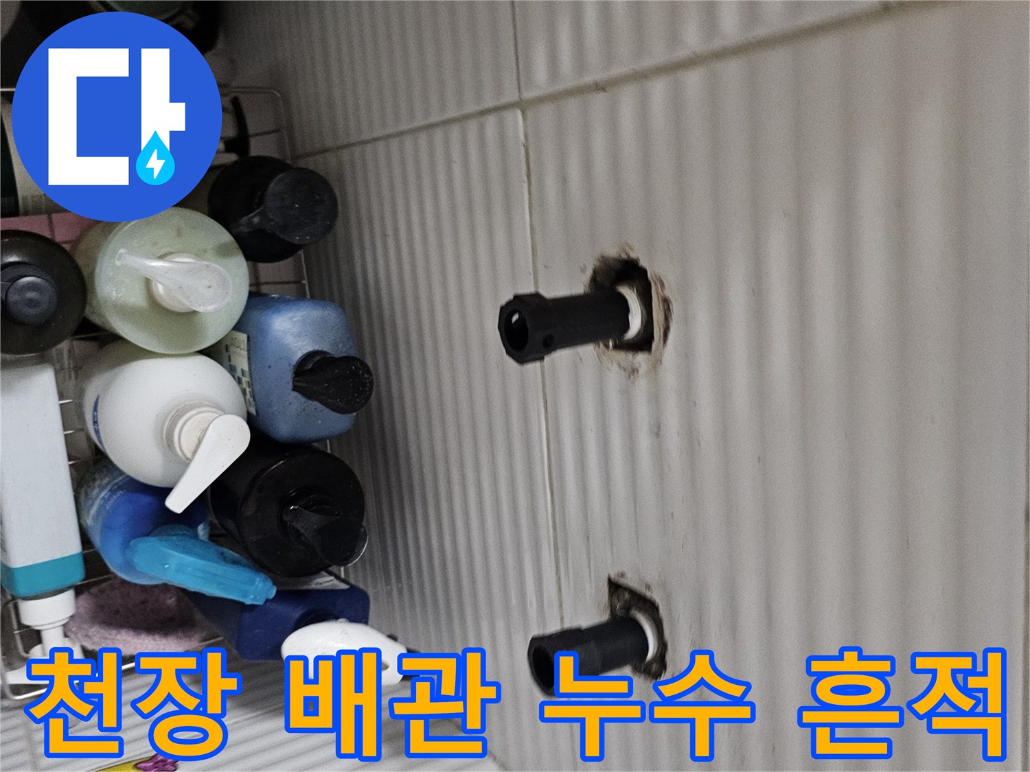 흰색 타일 천장에 노출된 두 개의 검은색 배관 주변 젖음 현상