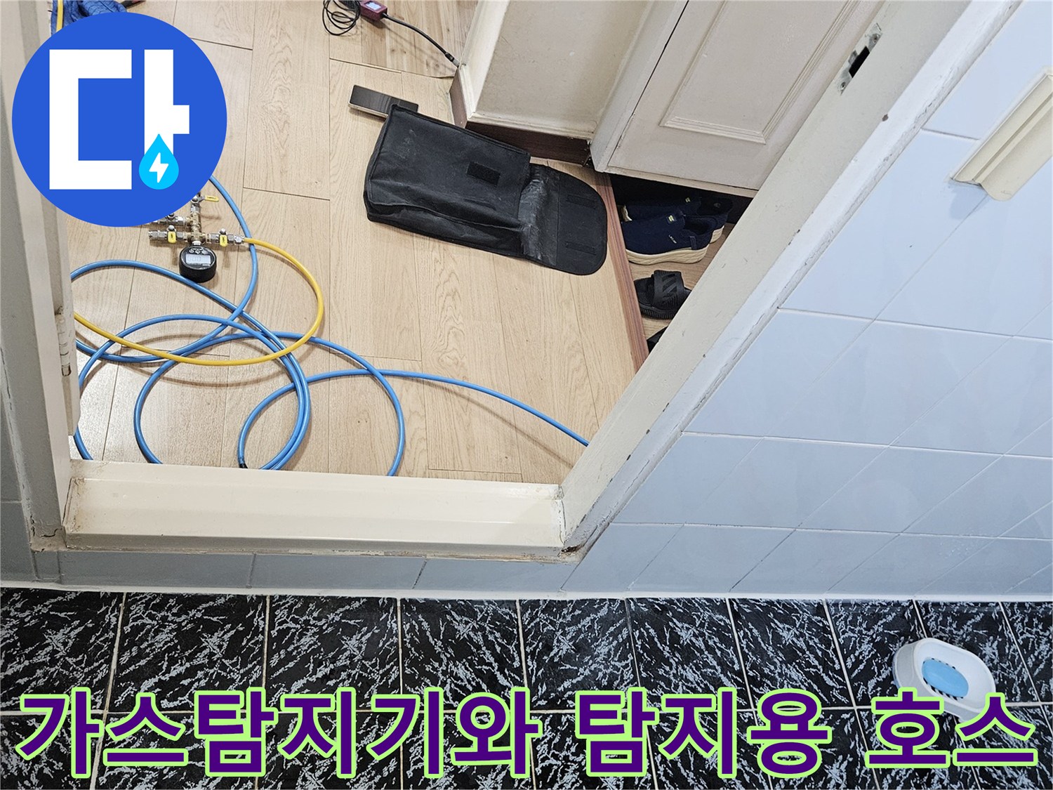 검은색 타일 바닥 위로 연결된 파란색과 노란색 가스 탐지용 호스 및 장비