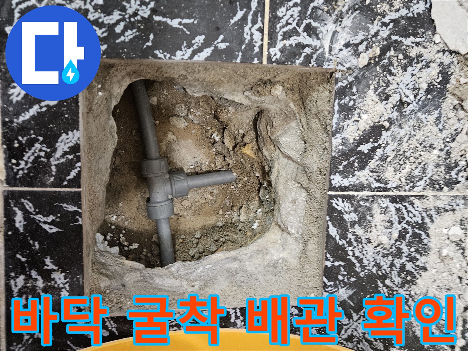 바닥 타일 아래 굴착된 부위에서 보이는 T자형 배관 연결부