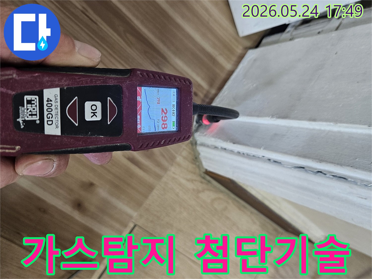 숙련된 누수 엔지니어가 가스 탐지기를 사용하여 벽면 하단에서 누수 반응을 면밀히 확인하고 있습니다.
