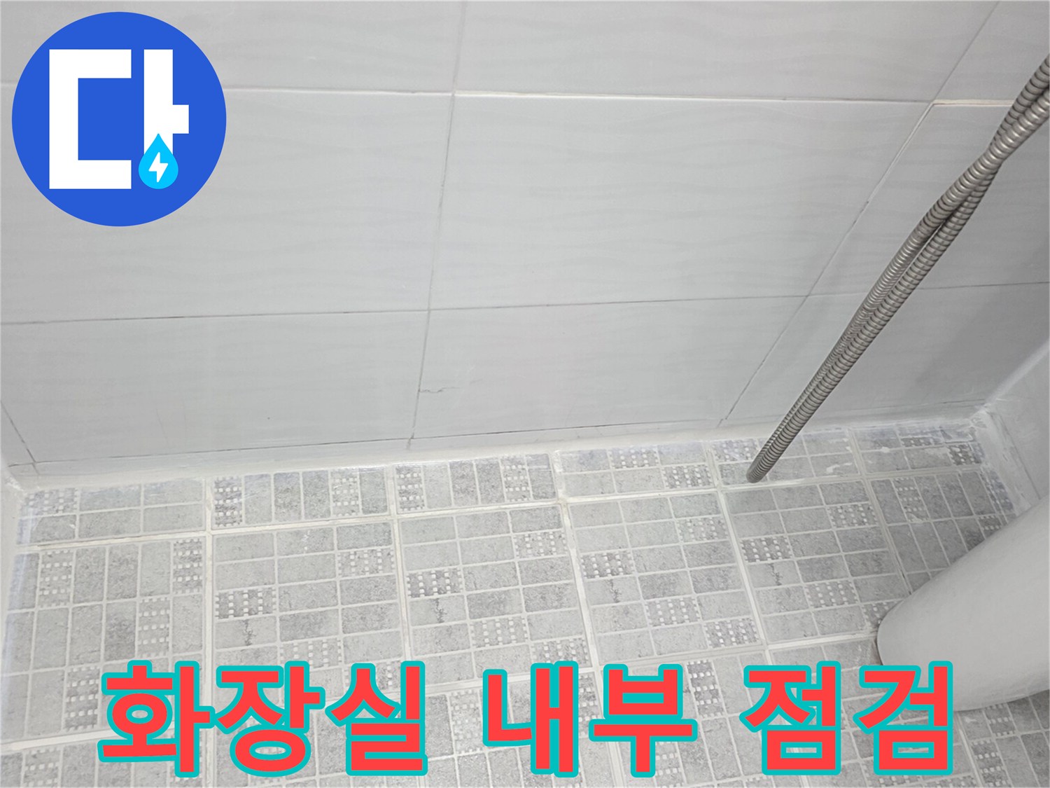 샤워기가 설치된 화장실 바닥과 타일 벽면의 모습입니다.
