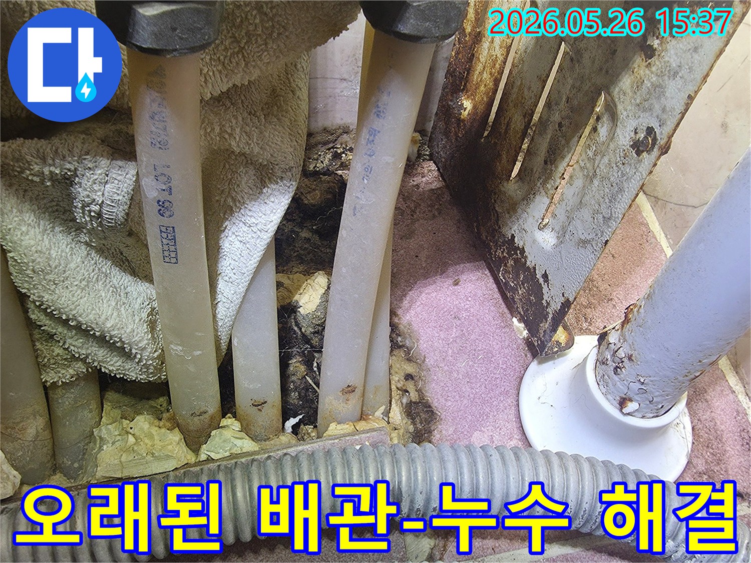 이 이미지는 오래된 배관 주변에서 발생한 물샘-누수 흔적과 부식된 금속을 보여줍니다.