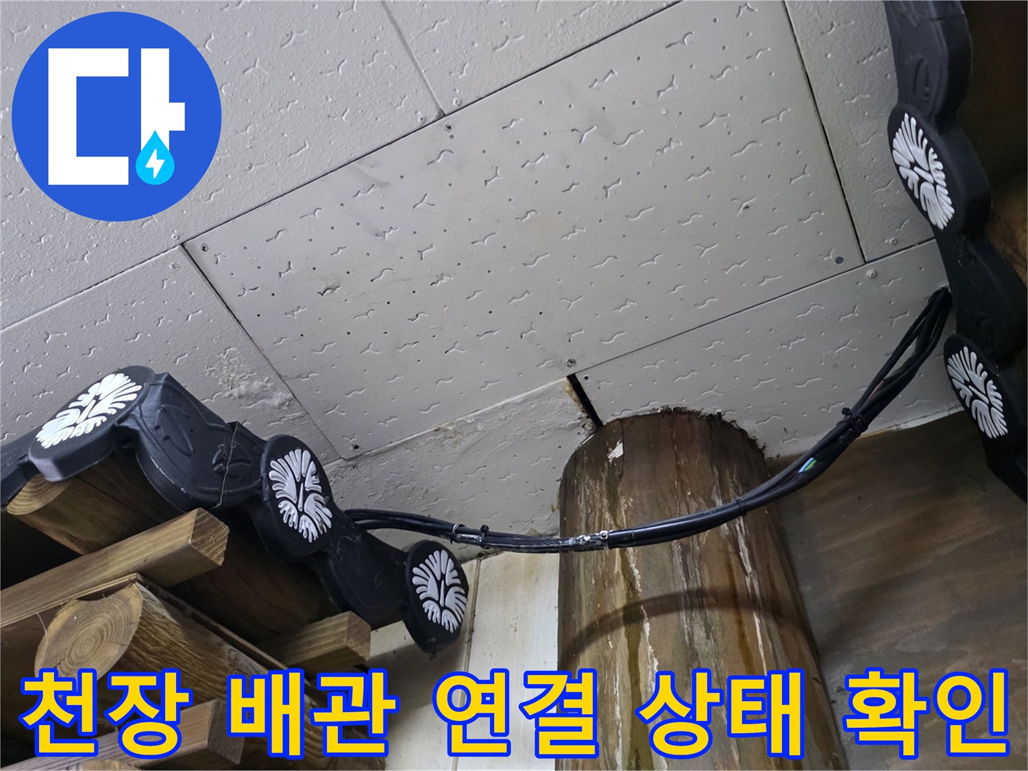 흰색 천장판 아래에 설치된 검은색 호스와 배관 부속품