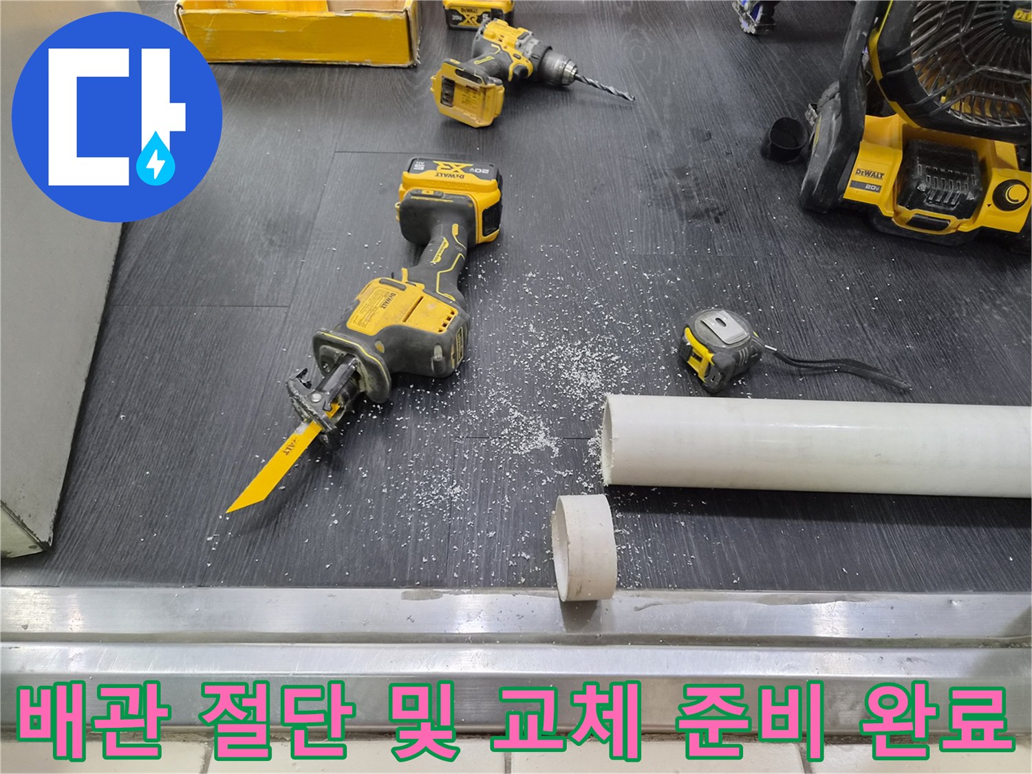 잘려나간 하얀색 배관과 전동 공구가 놓인 작업 바닥