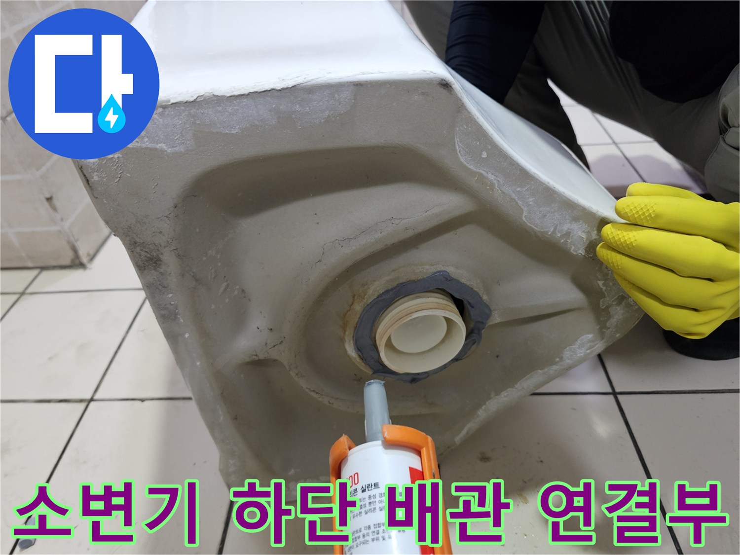 탈거된 소변기의 배관 입구와 작업용 실리콘 건의 모습