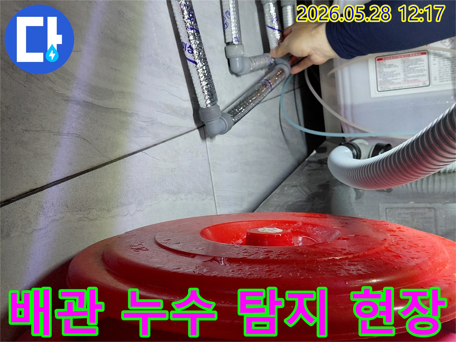 누수 엔지니어가-젖은 바닥과-배관 연결부를-면밀히 살피며-누수 원인을-찾고 있습니다.