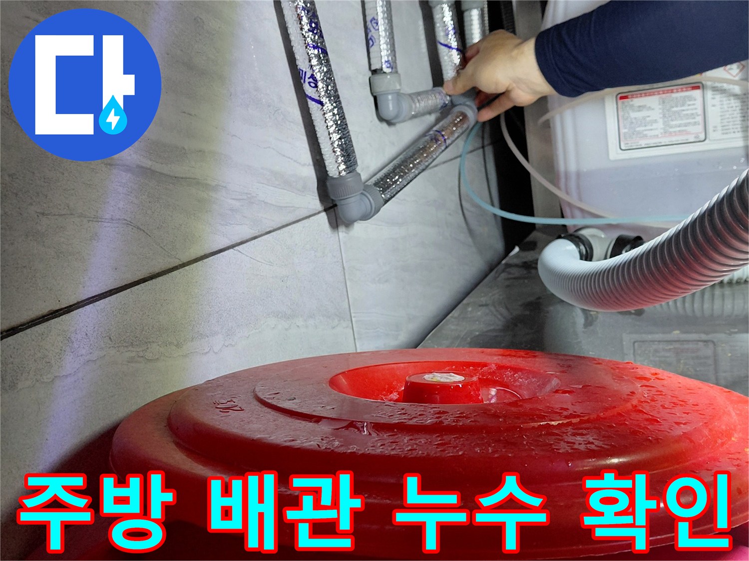 싱크대 하단 에이콘 배관의 연결 부위를 손으로 점검하는 모습