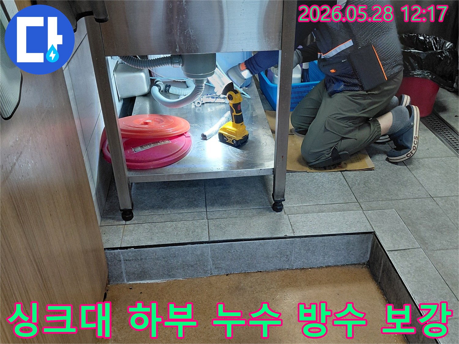 이 이미지는-전문 엔지니어가-주방 싱크대-아래의-누수 지점을-정밀하게 탐지하고-방수 보강 작업을-진행하여-누수를 해결하는-모습을-보여줍니다
