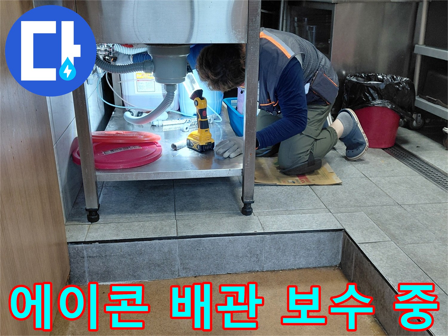 좁은 싱크대 밑 공간에서-배관 연결 상태를 확인하는 작업자