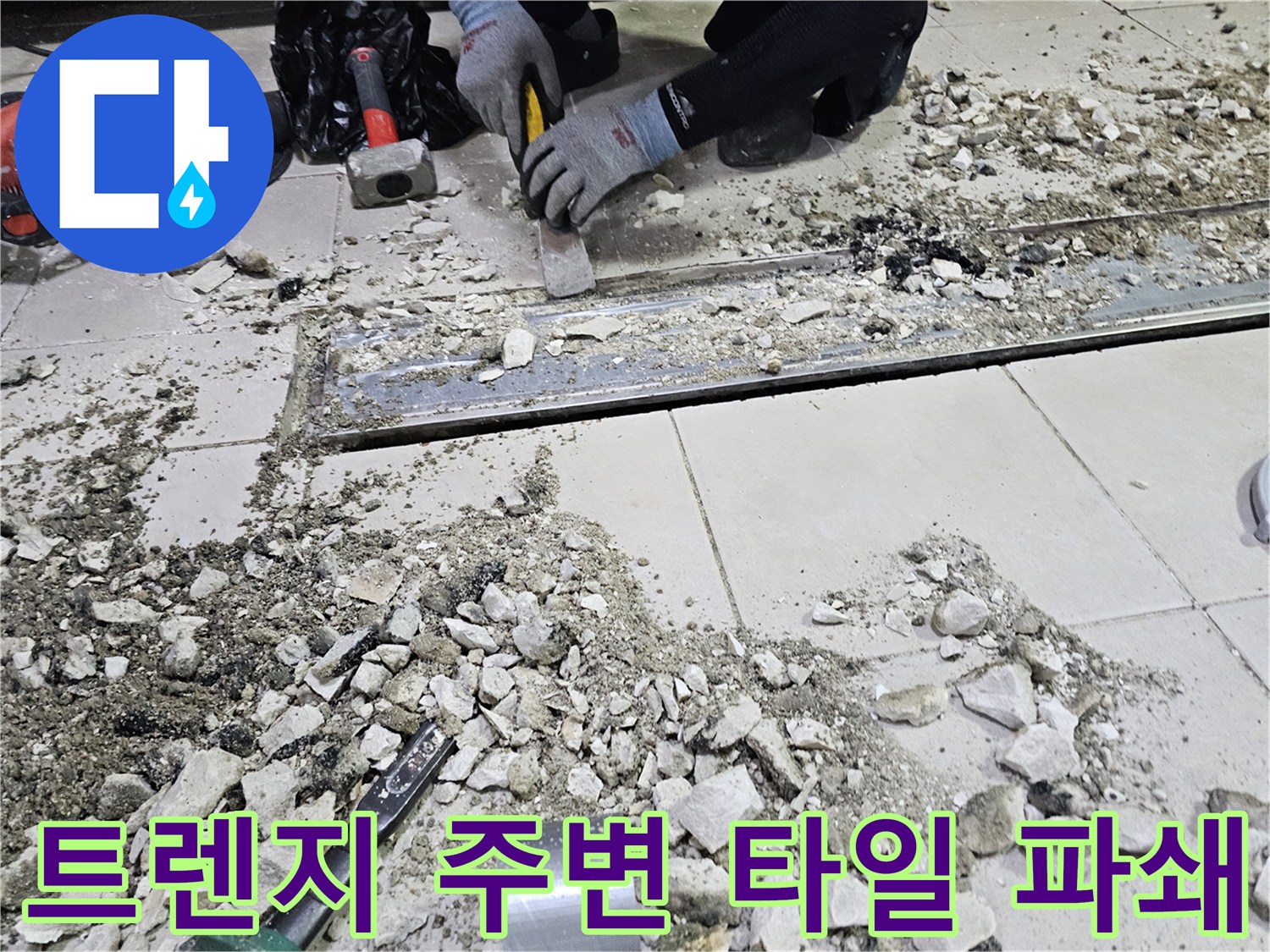 식당 주방의 배수 트렌치 주변 타일을 제거하여 누수 지점을 드러내는 작업 장면입니다.