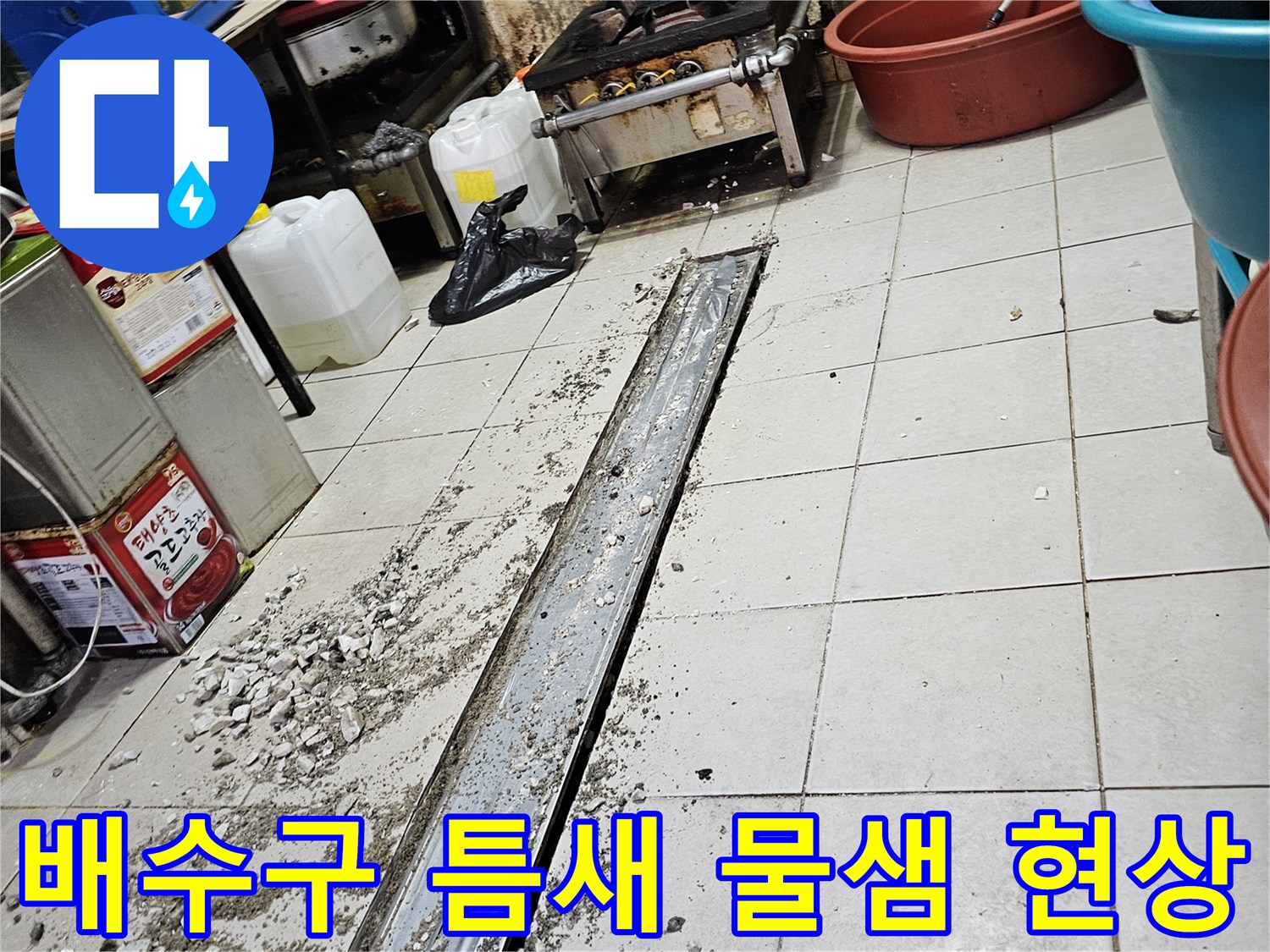 주방 배수 트렌치의 벌어진 틈과 주변 타일의 상태를 보여주는 사진입니다.