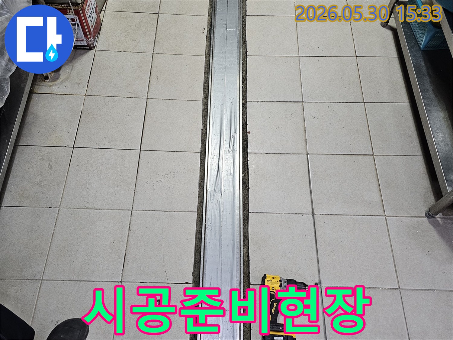 타일 바닥과-배수 트렌치-그리고 작업용 전동 드릴이 놓인-누수 보수-정확한 시공 준비-현장입니다