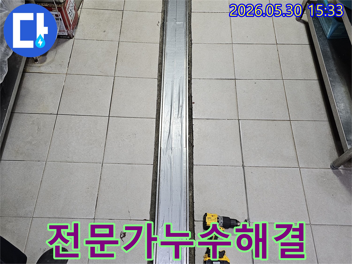 타일 바닥과-배수 트렌치-그리고 작업용 전동 드릴이 놓인-전문가의 손길로-누수 해결-준비 현장입니다