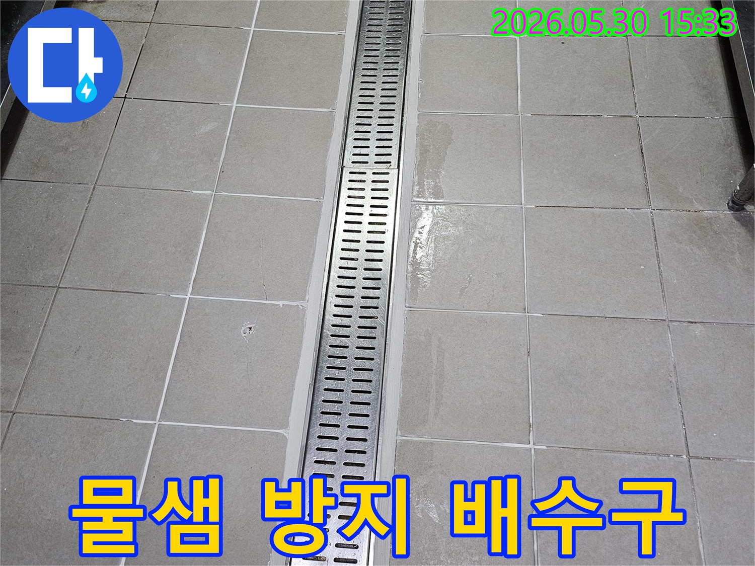 타일 벽면에-새롭게 설치된-스테인리스 선형 배수구-물이 고이지 않고-빠르게 배수되도록-시공된 모습