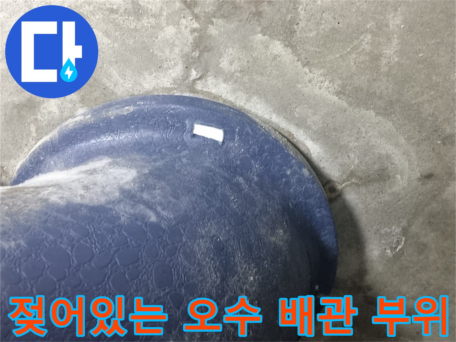 푸른색 배관과 젖은 콘크리트-오수관 주변의 습기 침투 상태를 촬영한 이미지입니다.