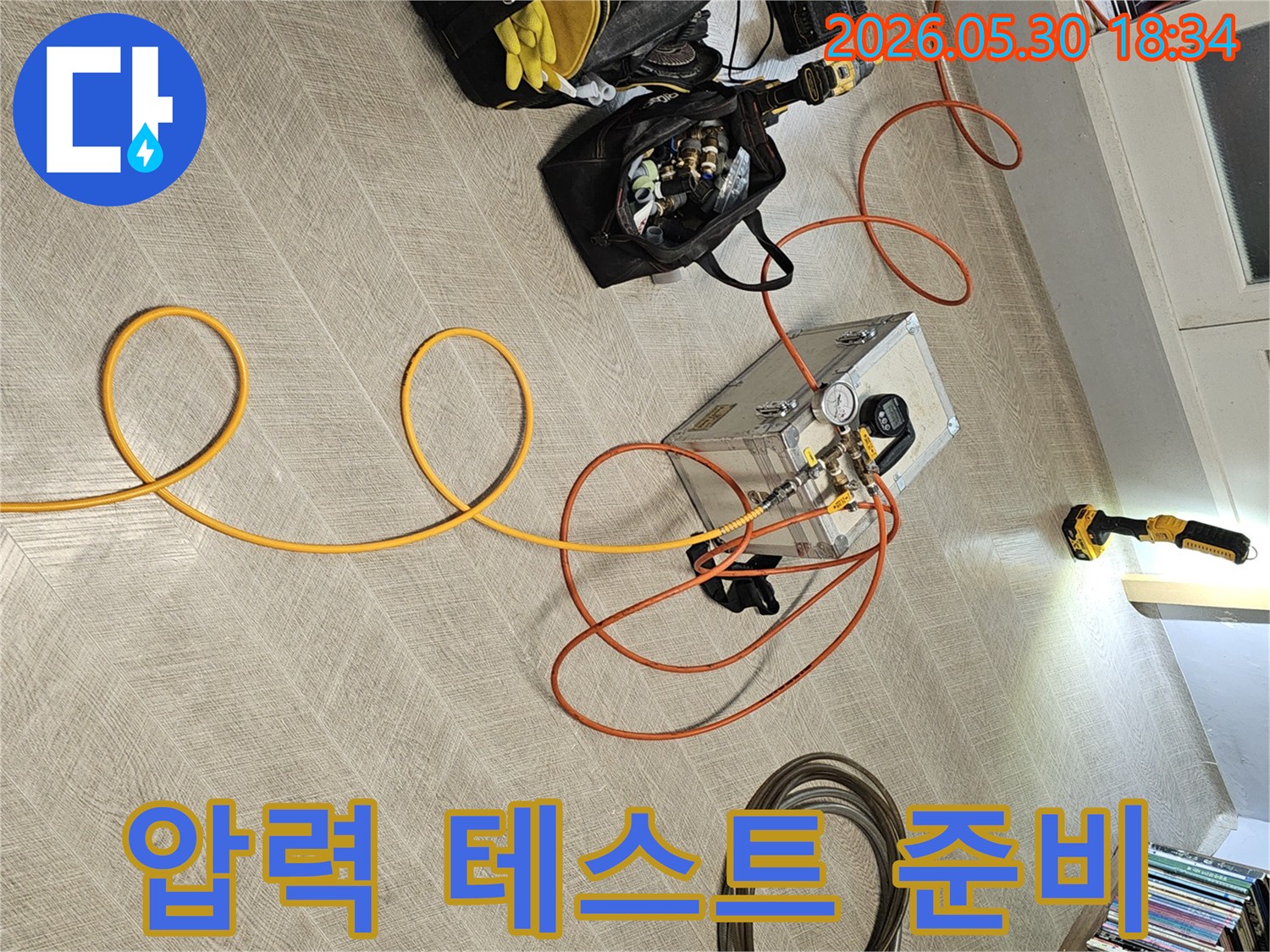 누수 원인을 정확히 파악하기 위해-다양한 전문 공구와-압력 측정 장비를-실내 바닥에 설치하는 현장 사진입니다.