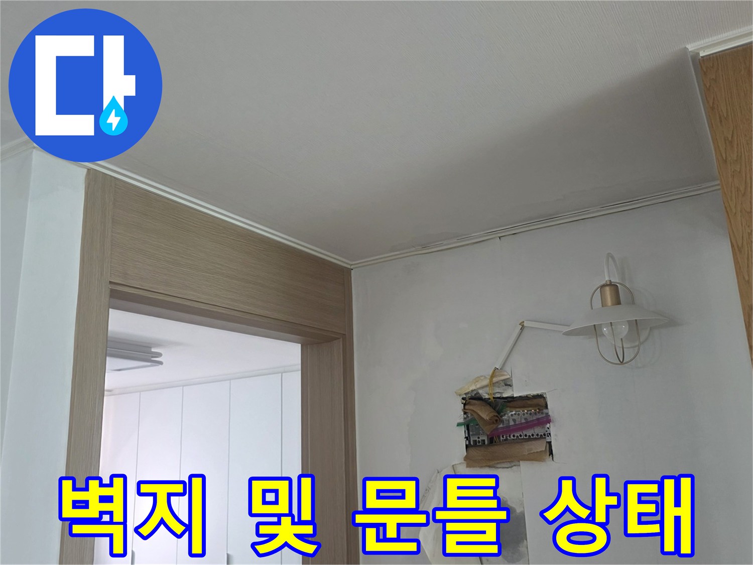 물샘 흔적이 남아있는 거실 벽지와 나무 문틀 부위