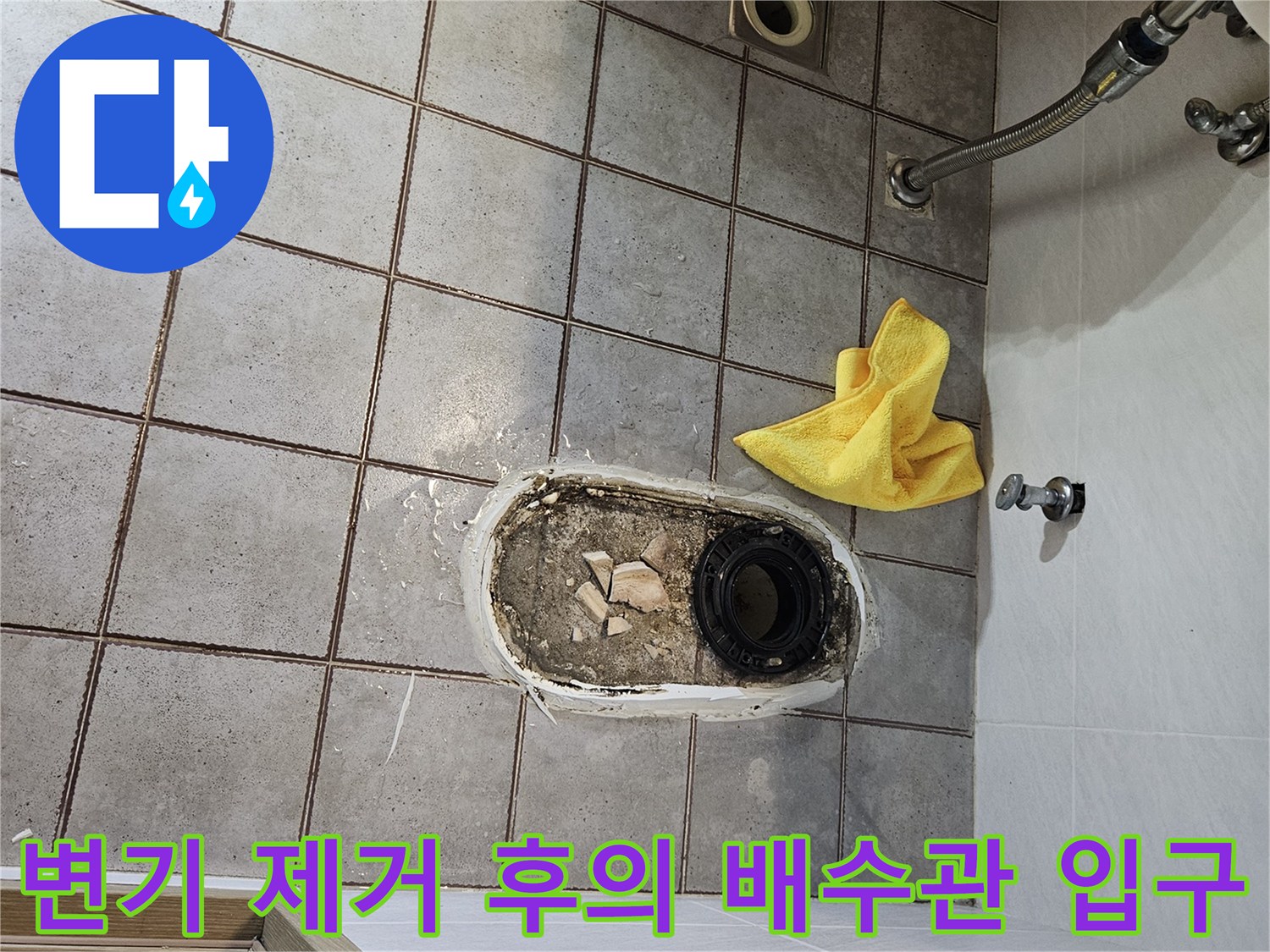 변기를 들어낸 자리의 검은색 배수관과 주변의 부서진 자재들