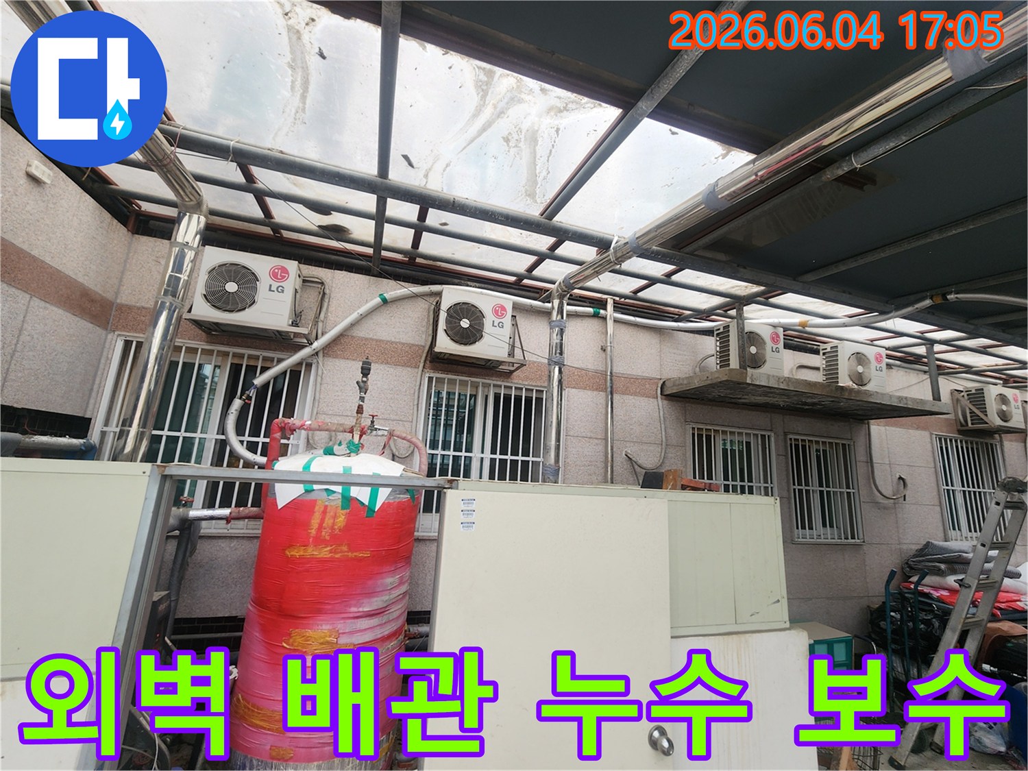 이 이미지는 오래된 건물 외벽에 설치된-다양한 배관들과-에어컨 실외기들이-복잡하게 얽혀있는 모습을 보여줍니다