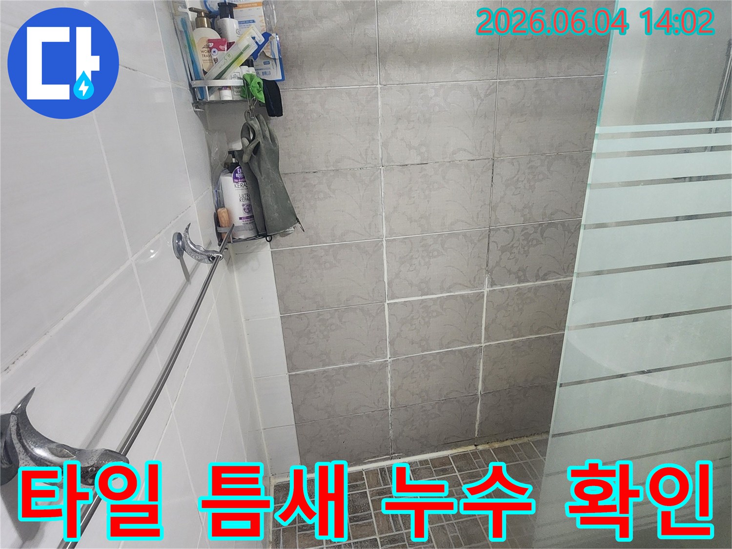 욕실 벽면의-회색 타일과-하얀색 줄눈 사이를-면밀히 관찰하며-미세한 누수 흔적을-찾는 모습입니다